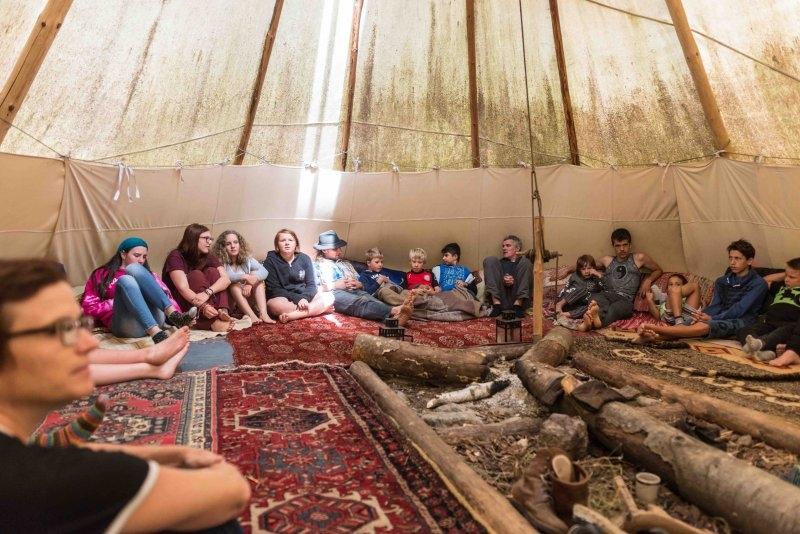 Teilnehmer eines Abenteuer Forschercamps sitzen im Tipi