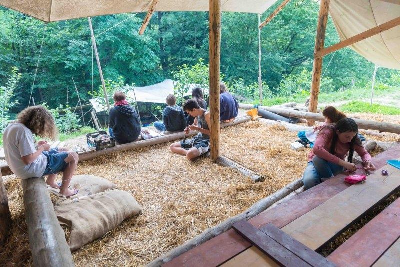 Kinder eines Abenteuer Forschercamps schnitzen