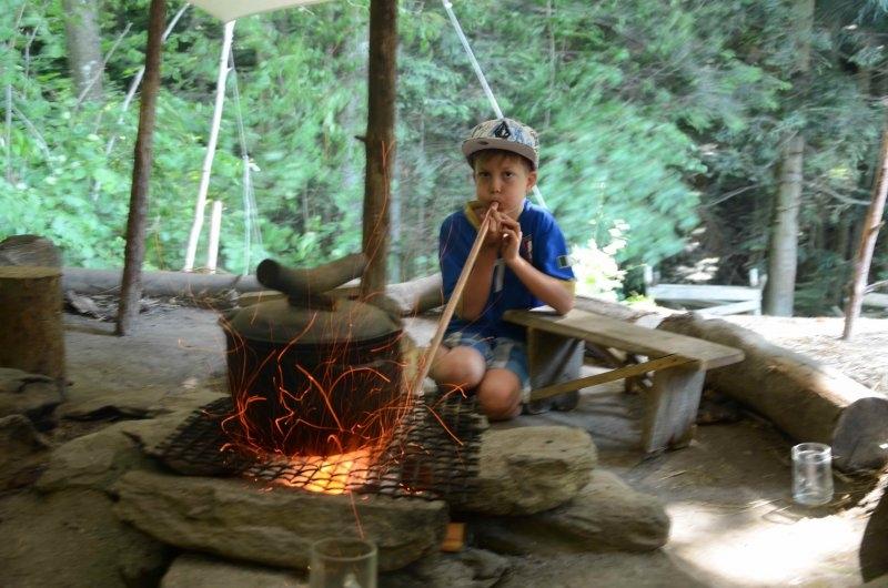 Ein Junge eines Abenteuer Forschercamps pustet