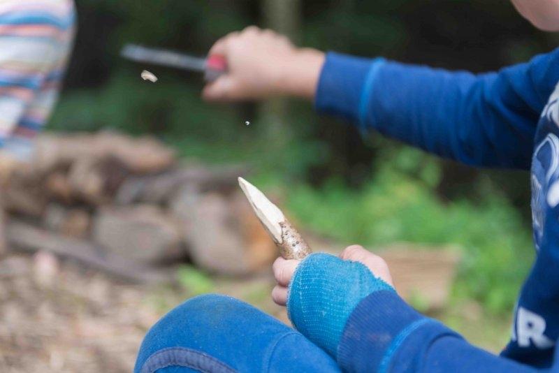 Kinder eines Abenteuer Forschercamps schnitzen