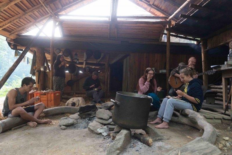 Kinder eines Abenteuer Forschercamps sitzen unter einem Dach