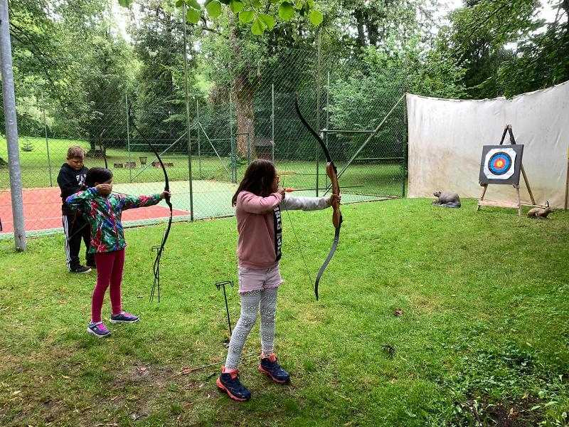 Teilnehmer eines Sportlagers schießen mit Pfeil