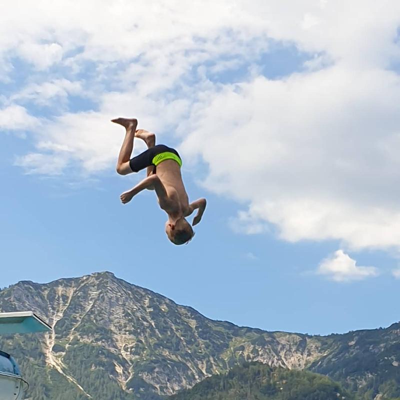 Teilnehmer eines Sportlagers springen in den See