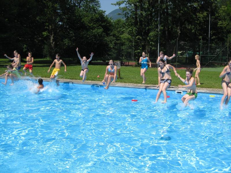 Teilnehmer eines Sportlagers springen in den Pool