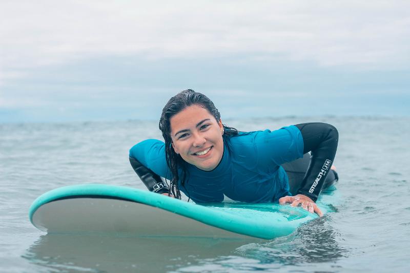 Ein Mädchen des Spanien Surfcamps liegt auf dem Board