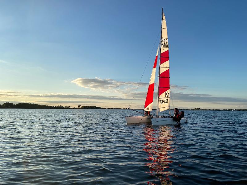 Teilnehmer eines Feriencamps am Wasser segeln