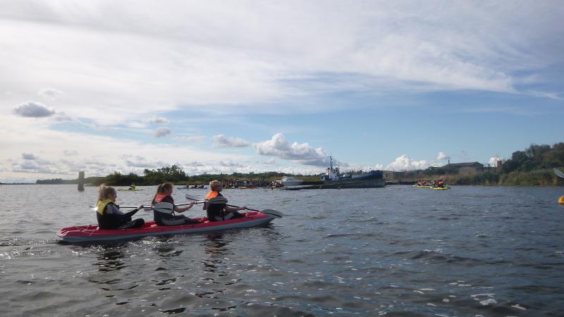 Drei Teilnehmer eines Feriencamps am Wasser fahren Kajak