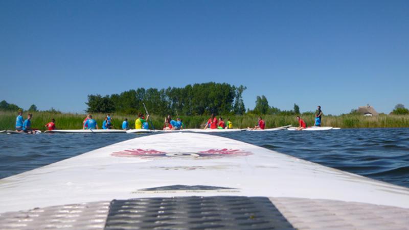 Kinder eines Feriencamps am Wasser machen Yoga