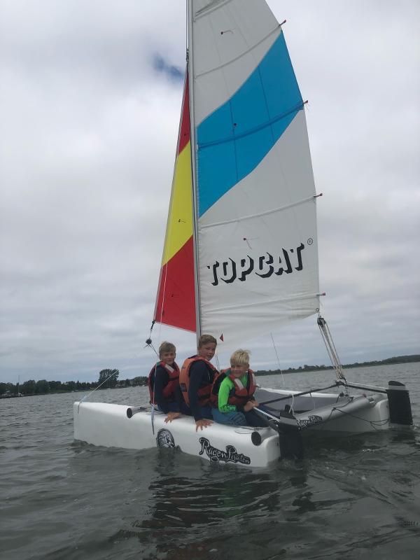 Drei Leute eines Feriencamps am Wasser segeln