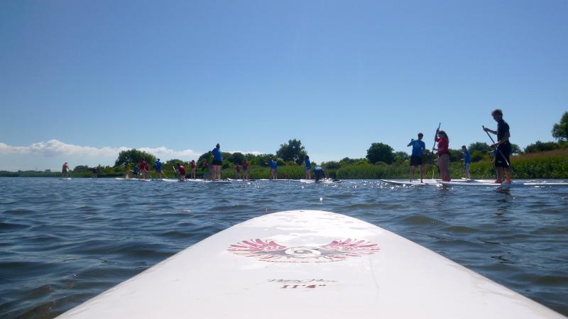 Ein Junge eines Feriencamps am Wasser fährt SUB