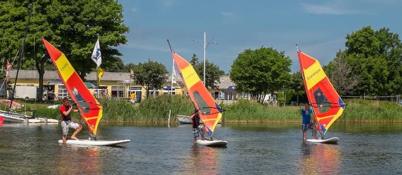 Drei Jugendliche legen grade im Windsurfcamp aus dem flachen Bereich des Wasser ab.
