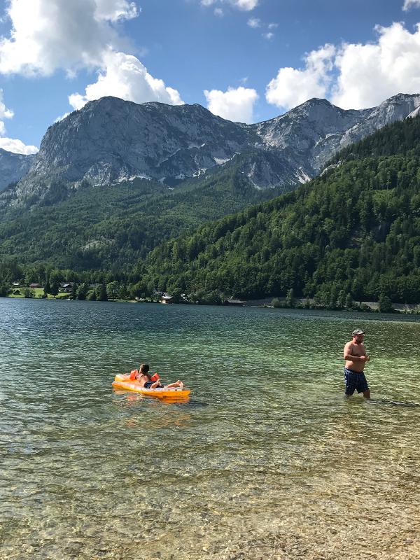 Beim Outdoorcamp liegt ein Kind im Wasser des Sees auf einer Luftmatratze