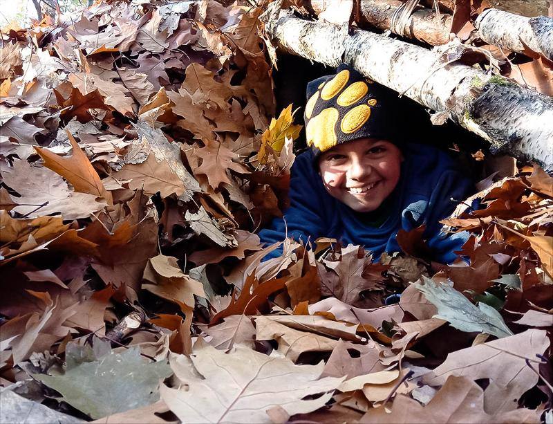 Ein Junge eines Zeltcamps versteckt sich im Laub