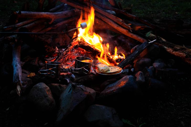 Teilnehmer eines Zeltcamps grillen Marshmellos