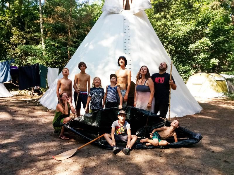 Teilnehmer eines Zeltlagers stehen vor ihrem Tipi