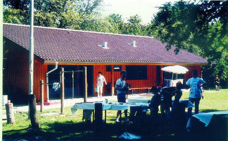 Teilnehmer eines Feriencamp Hannover stehen im Schatten an Tischen