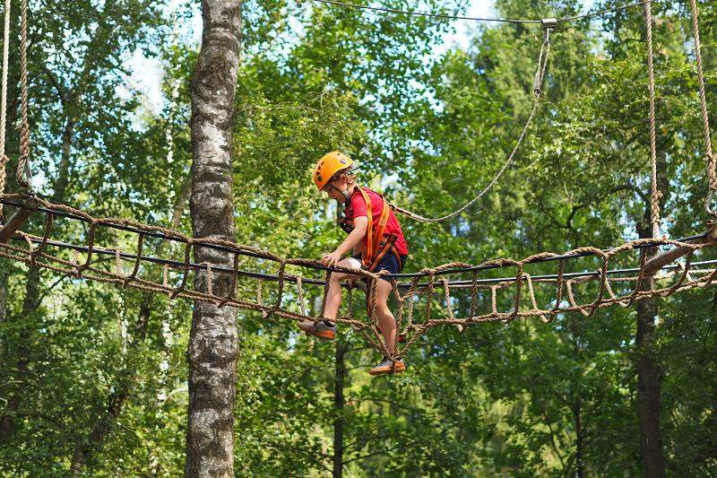 Ein Junge klettert im Sportcamp durch den Hochseilgarten