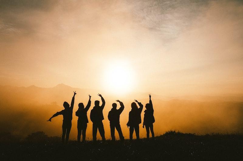 Teilnehmer eines Ferienlager in der Schweiz stehen im Sonnenaufgang