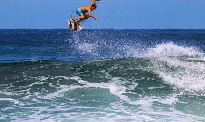 Ein Surfer macht auf Portugal Sprachreise einen Sprung im Wasser