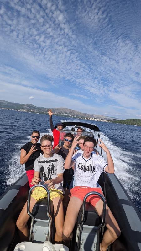 Eine Gruppe von Jugendlichen posiert auf einem Schnell Boot auf dem Meer in der Nähe der Küste bei einer der Jugendreisen ab 16 Herbstferien