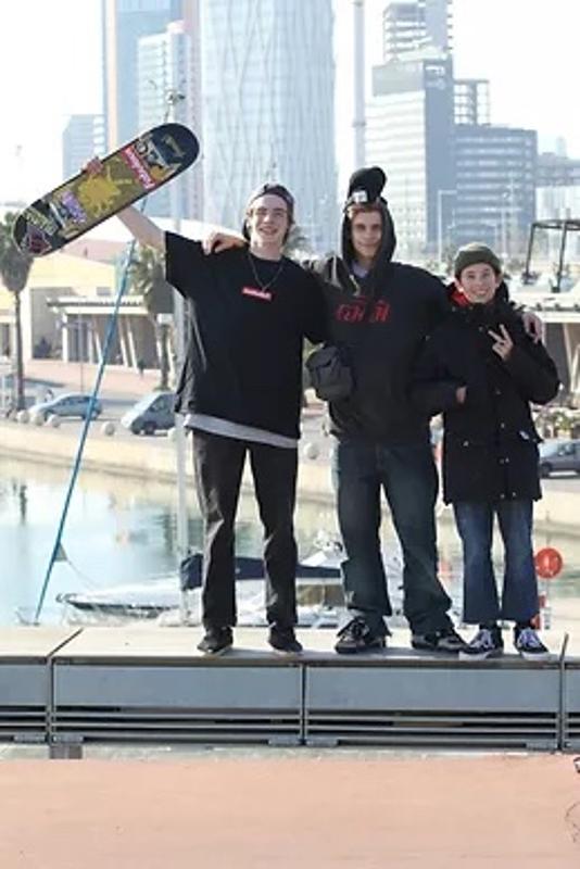 Jungs halten bei ihrer Jugendreise Callela ein Skateboard hoch