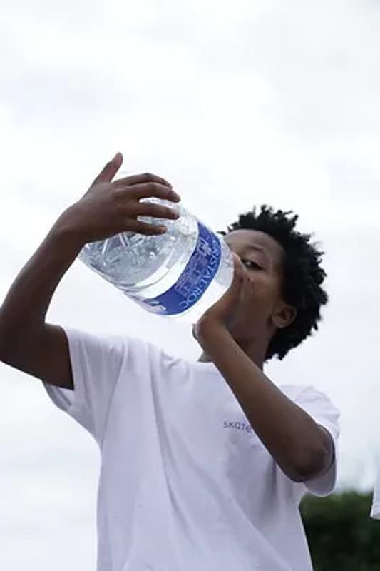 Ein Junge trinkt bei seiner Jugendreise Calella aus einer großen Wasserflasche