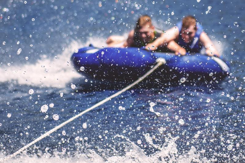Zwei Jungs liegen während der Sprachreise im Wasser auf einem Reifen und werden gezogen