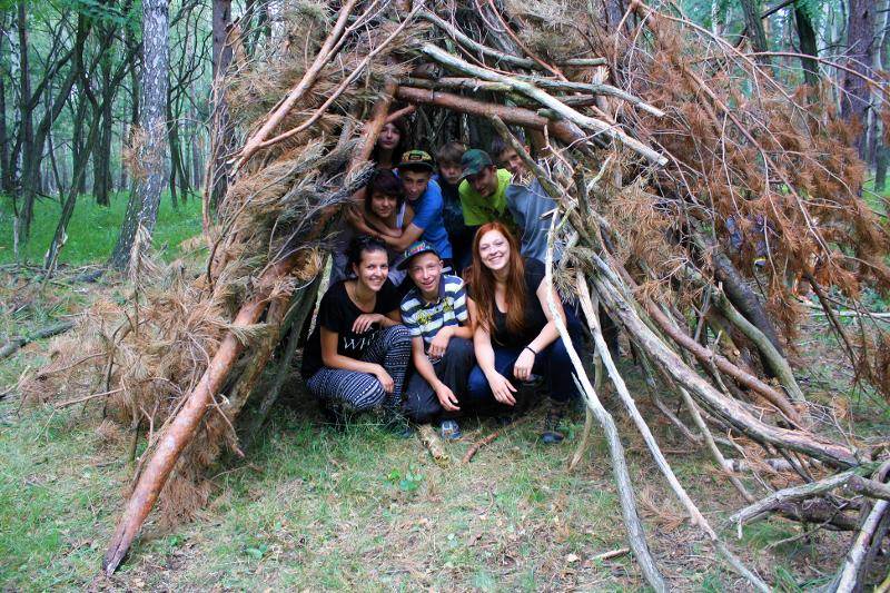 Die Kinder haben sich im Outdoor Camp im Wald einen kleinen Unterschlupf aus Stöckern gebaut