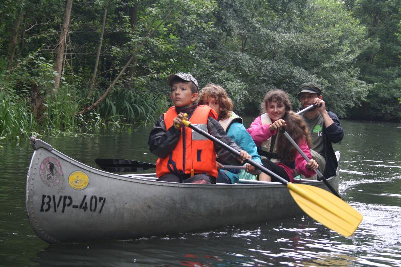 Kinder paddeln in einem Kanu im Outdoor Camp über einen Fluss