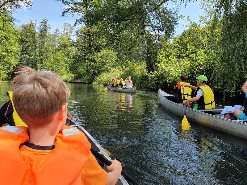 Die Kinder fahren im Outdoorcamp mit Kanus über einen Fluss