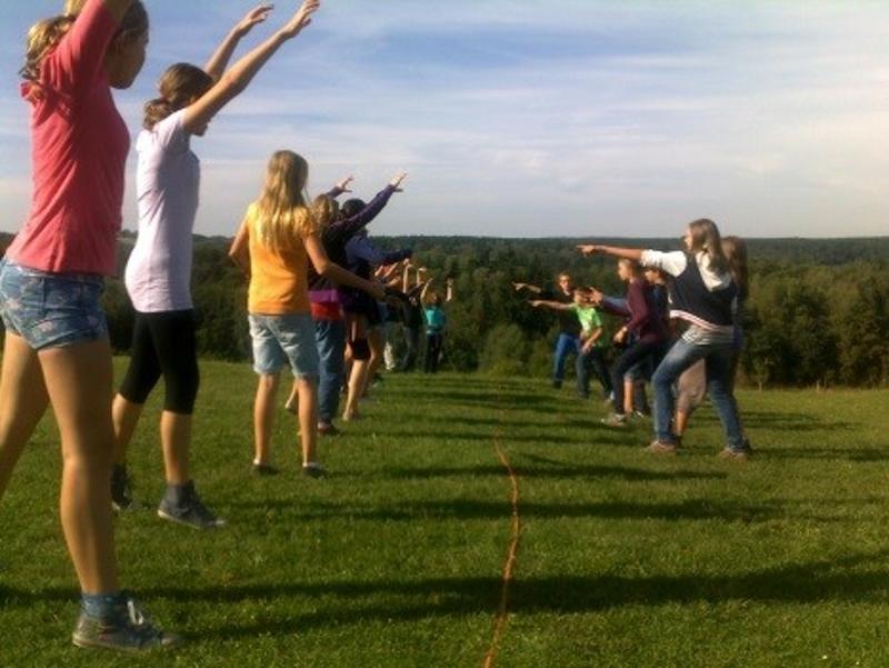 Die Kinder im Outdoor Camp stehen sich auf einer Wiese in zwei Reihen bei einem Spiel gegenüber