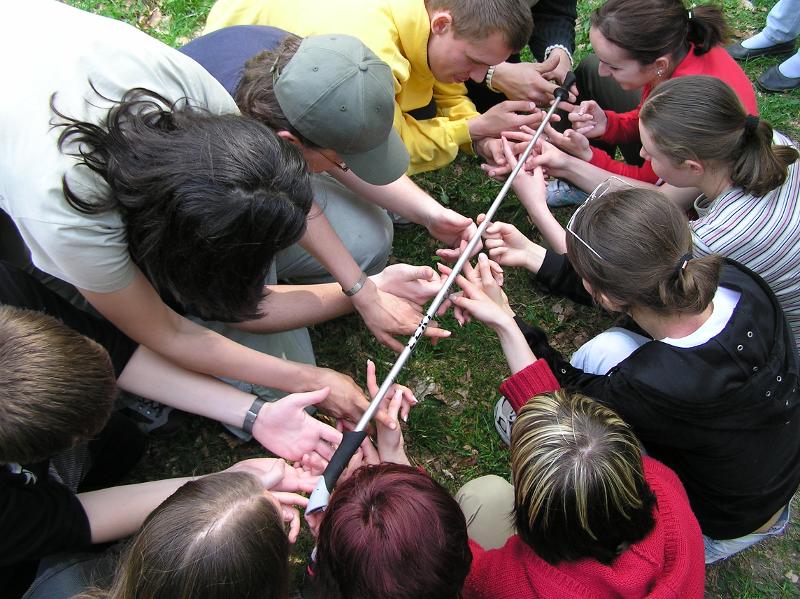 Die Kinder halten gemeinsam einen Stab im Outdoor Camp