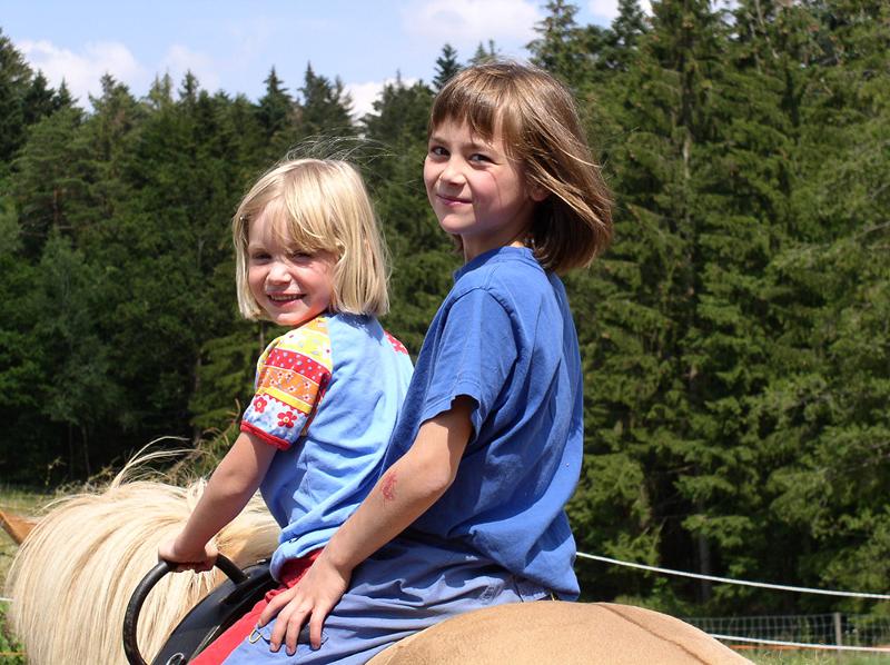In den Ferien auf dem Ponyhof gehen Kinder reiten