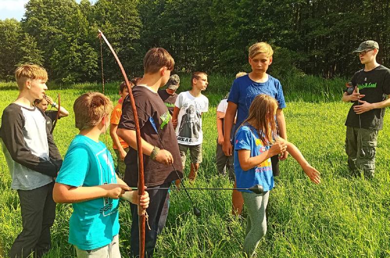 Ein Junge hält Pfeil und Bogen im Survival Camp in der Hand