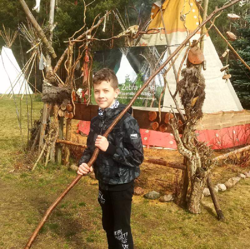 Ein Junge vom Survivalcamp hält einen langen Stock in der Hand