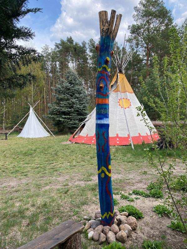 Vor den Tipis im Survivalcamp steht ein bunter Pfahl
