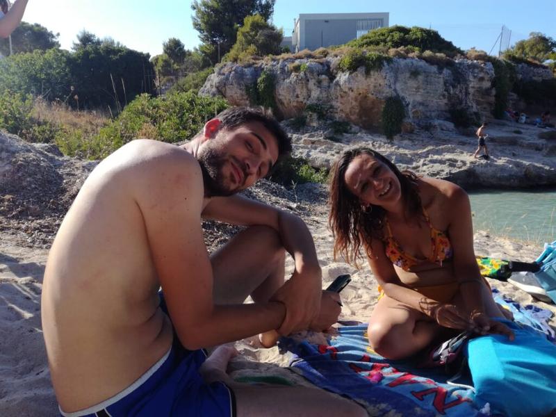 Zwei Teilnehmer der Sprachferien Italien sitzen auf Handtüchern am Strand