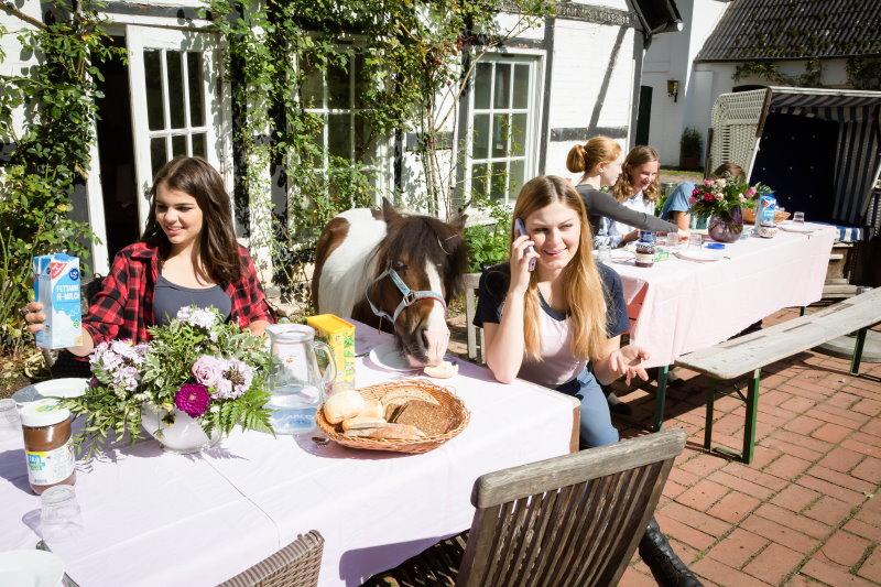 Kinder sitzen bei Lüneburger Heide Reiterferien an gedeckten Tischen