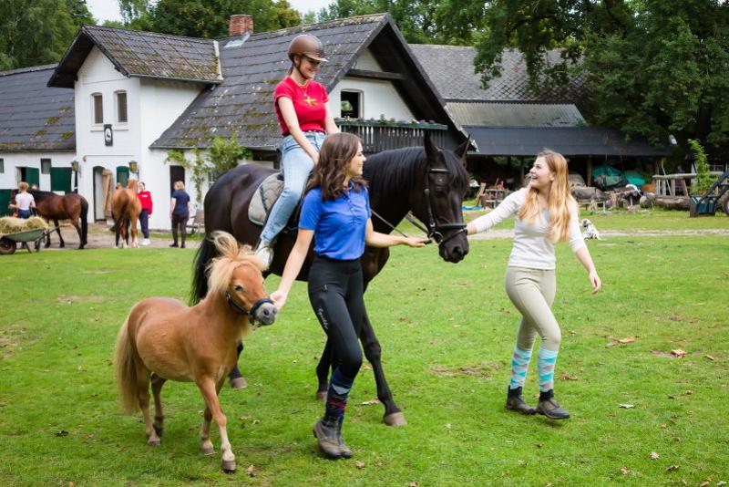 Kinder führen sich bei Reiturlaub Lüneburger Heide über eine Wiese