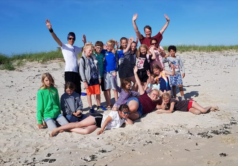 Eine Gruppe von Kindern steht mit ihren Betreuern vom Ferienangebot Hamburg am Strand