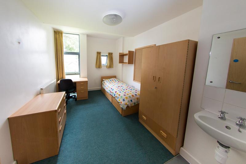 In einem kleinen Zimmer für Studenten auf Sprachreise stehen ein Beet, ein Schrank und ein Schreibtisch