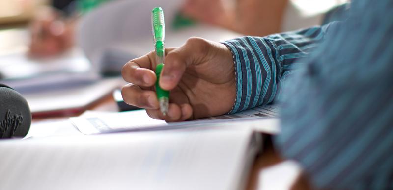 Ein Schüler schreibt auf England Sprachreise mit einem Stift etwas auf ein Blatt