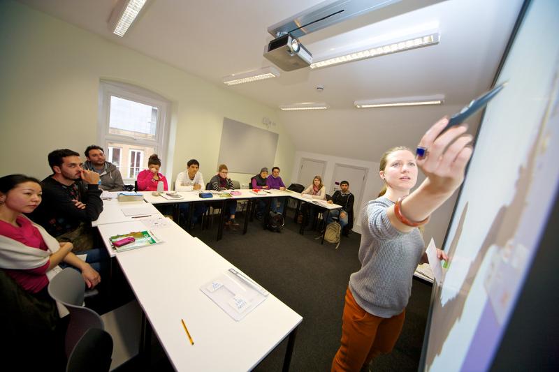 Eine Lehrerin zeigt auf Schülersprachreise England mit einem Stift etwas an einer Tafel