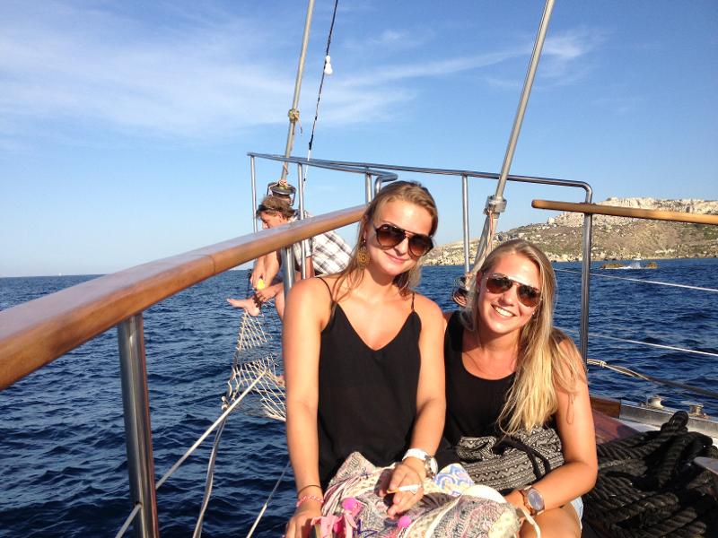 Zwei Mädchen sitzen auf Malta Sprachreise nebeneinander auf einem Boot und tragen Sonnenbrillen