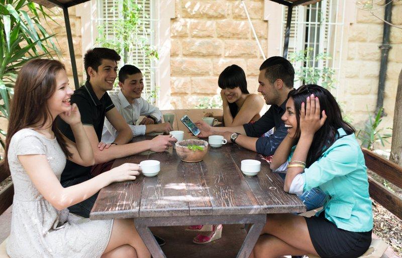 Eine Gruppe Jugendliche sitzt draußen am Tisch und hat Spaß zusammen bei den Sprachreisen Malta St. Julians 