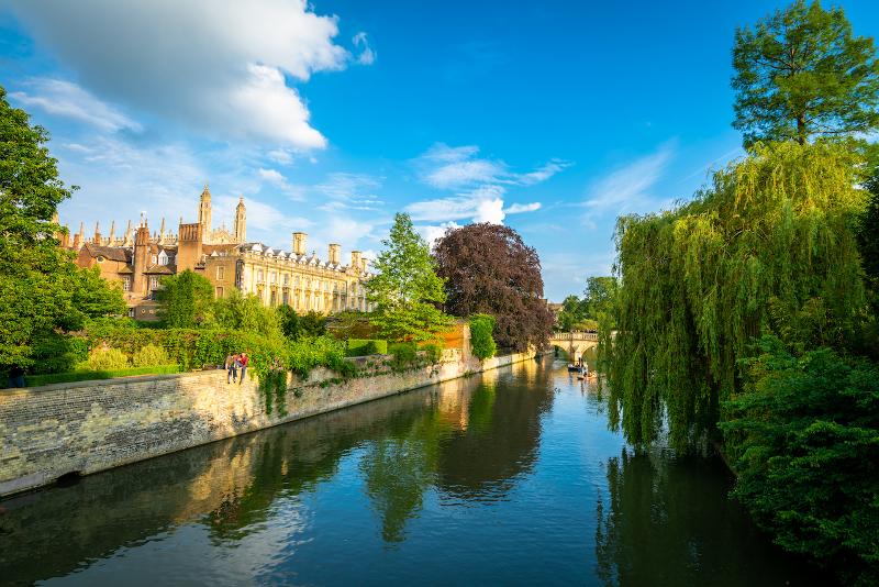 Ein Fluss zieht sich auf Sprachreise Cambridge neben großen Gebäuden und vielen Bäumen durch die Landschaft