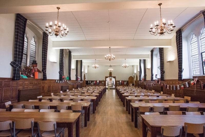 In einem großen Saal stehen auf Sprachreise England Schüler viele Stühle