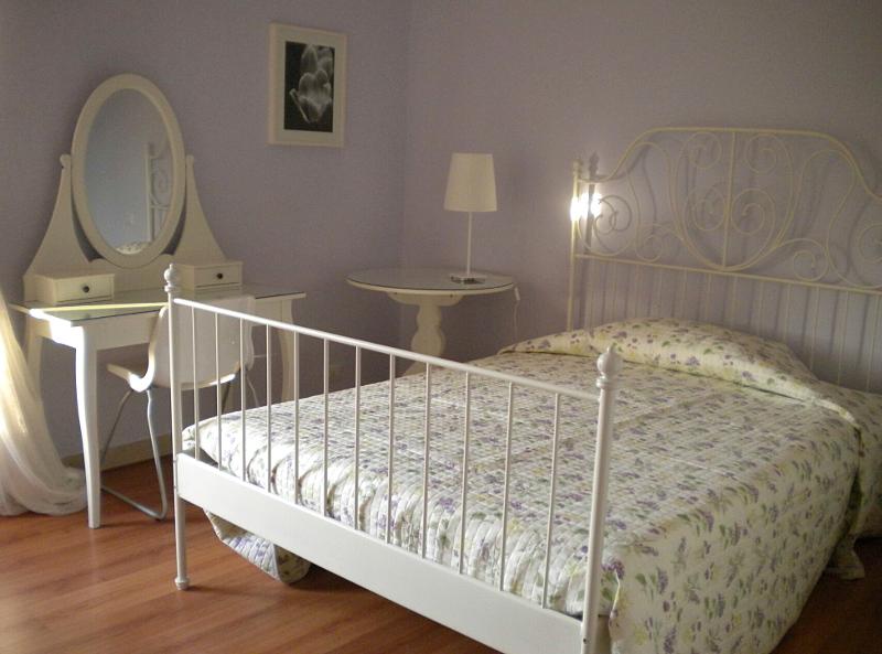 In einem Zimmer auf Sprachreise nach Italien steht ein Bett sowie ein Schreibtisch mit Spiegel