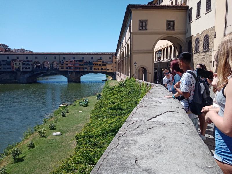 Schüler stehen auf Sprachreise nach Italien an einer Mauer und schauen auf einen Fluss mit einer Brücke