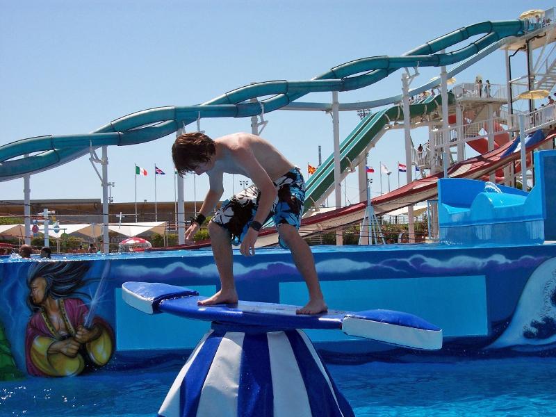 Ein Junge steht auf Sprachreise nach Italien in einem Wasserpark auf einem Surfbrett